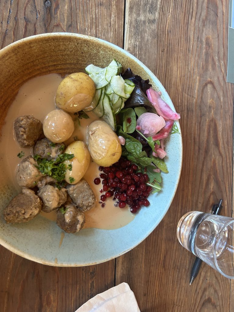 A plate with meatballs, small, yellow potatoes, and a salad.