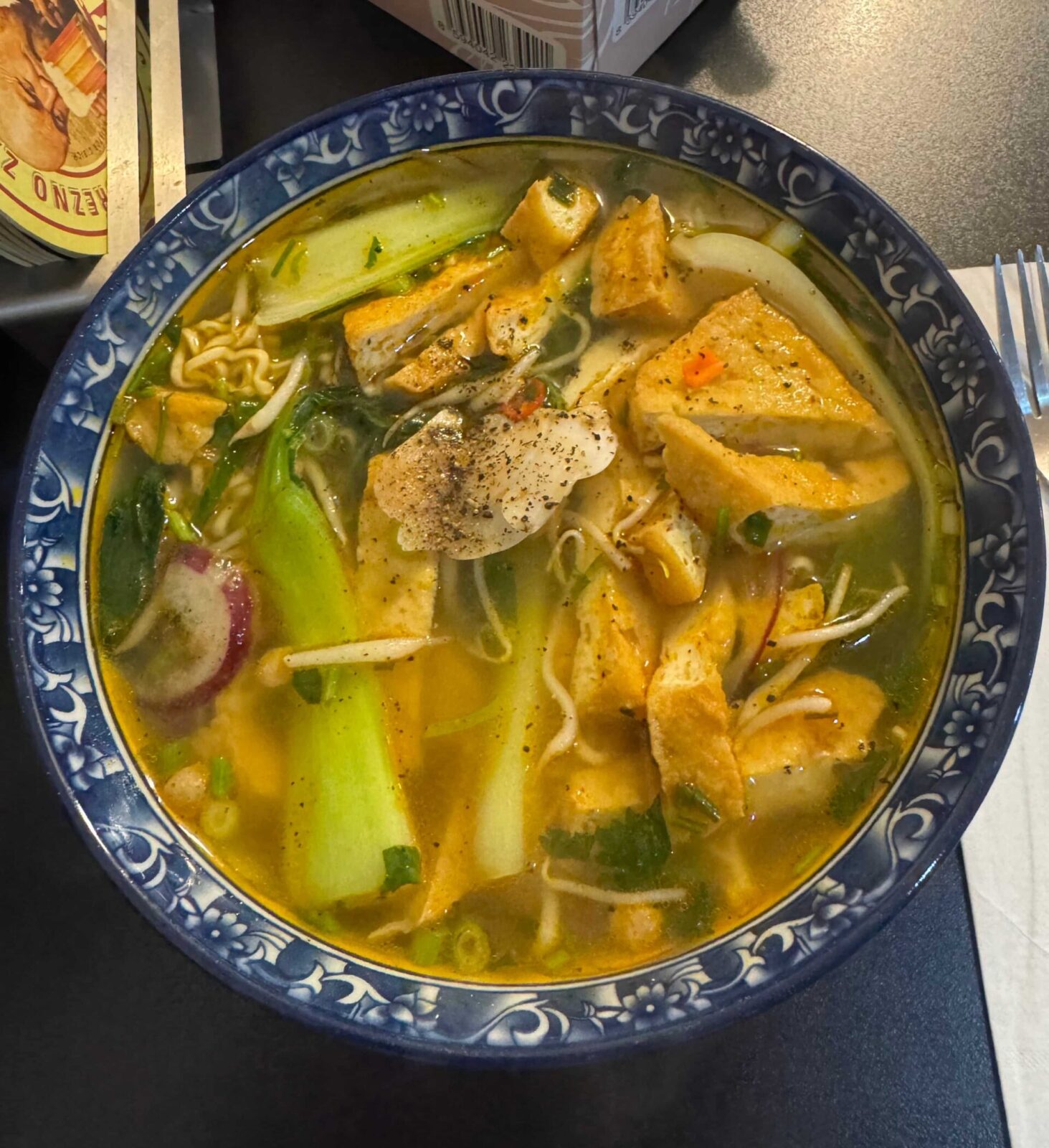 A bowl of soup with various meat and vegetables in a blue bowl