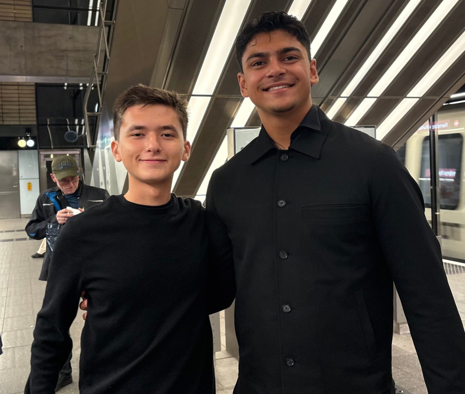 Two people standing side-by-side, smiling for a photo. 
