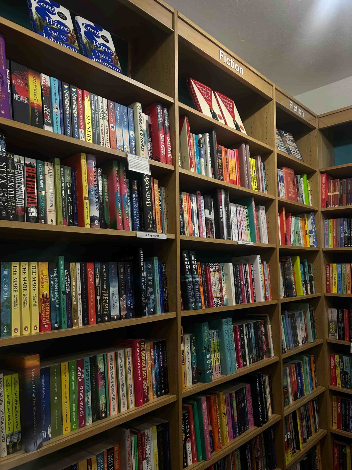 Brown bookshelves filled with an assortment of fiction books.
