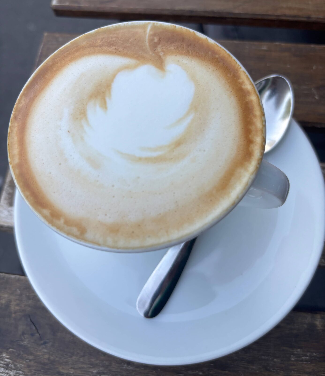 A mug of coffee, with a small spoon next to it, on a small plate.